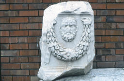 Stone artefact in museum garden, human face